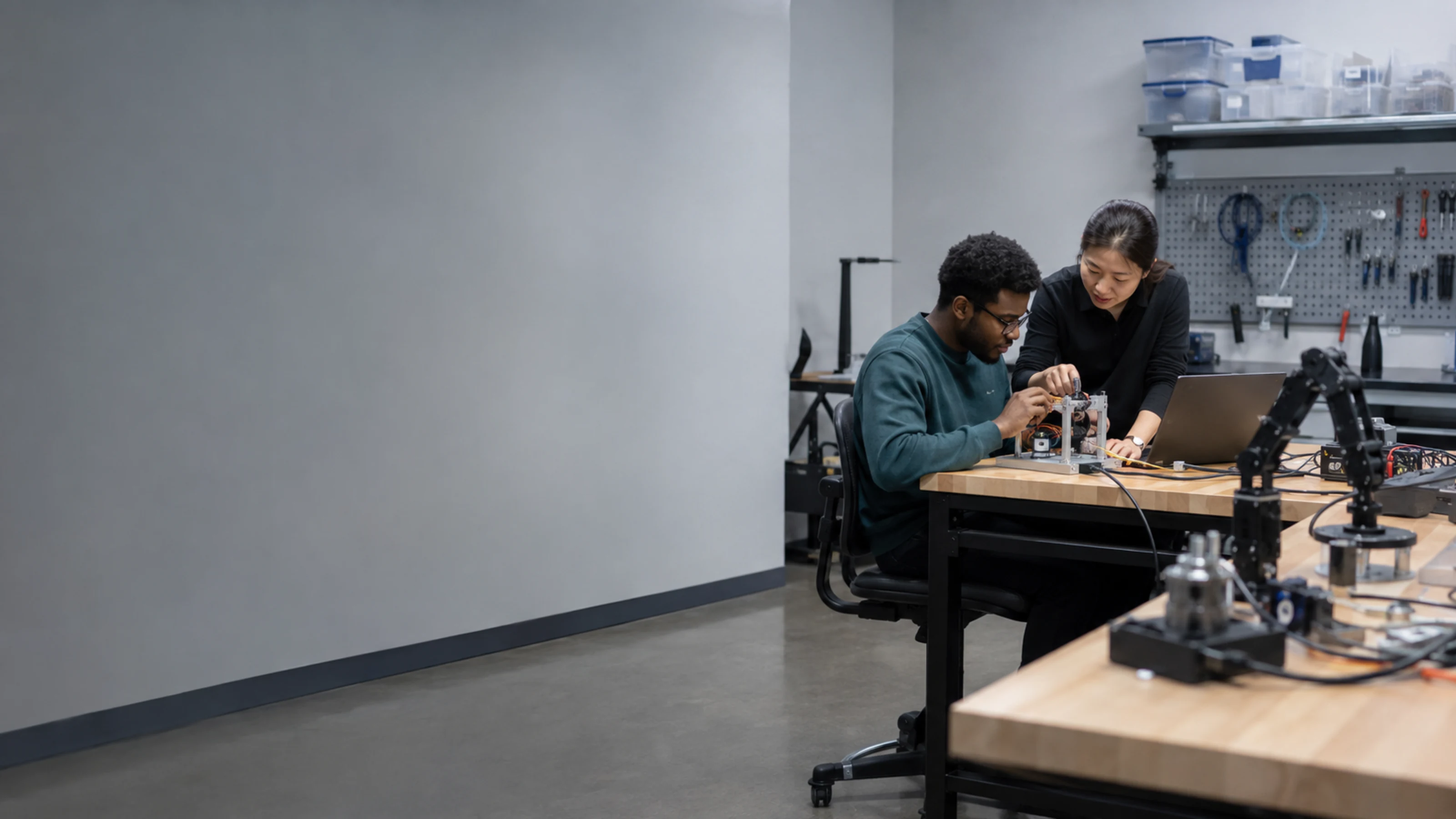 Student researcher and PhD mentor calibrating a robotic test rig in a university lab